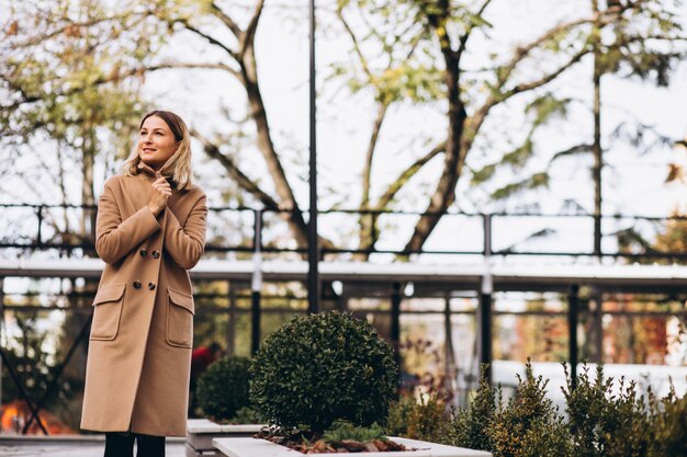 Beautiful woman in a beige coat outside in park