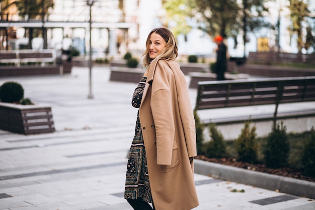 Beautiful woman in a beige coat outside in park