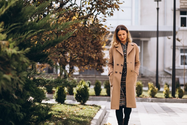 Free photo beautiful woman in a beige coat outside in park