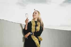 Free photo beautiful woman in black dress holding a glass of champagne