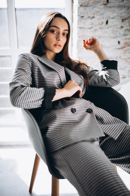 Free photo beautiful woman in a business suit sitting in chair