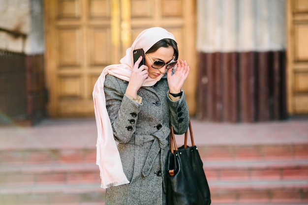 Free photo beautiful woman in coat speaks by phone on the street