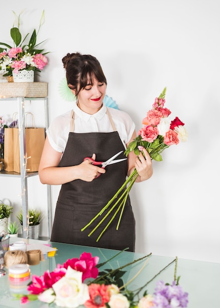 Beautiful woman cutting twigs of flowers with scissors