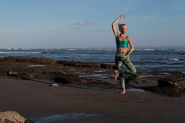 Beautiful woman doing yoga on the beach