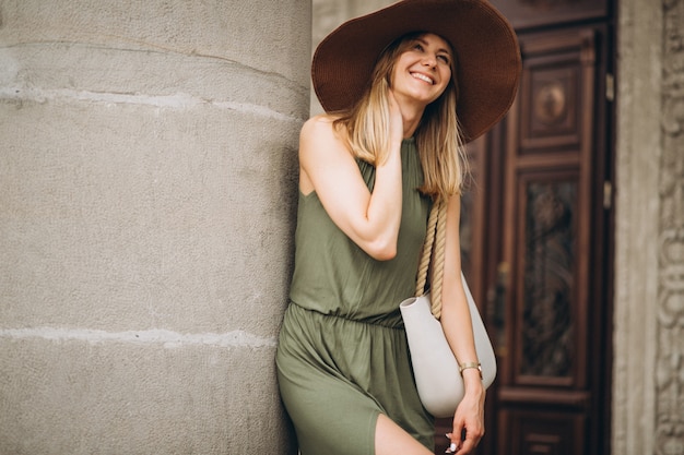 Free Photo beautiful woman in dress and hat standing by architecture