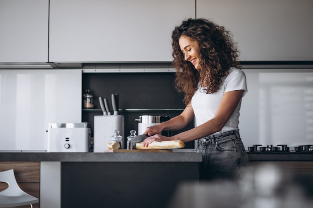 Beautiful woman eating fresh bread at the kitchen