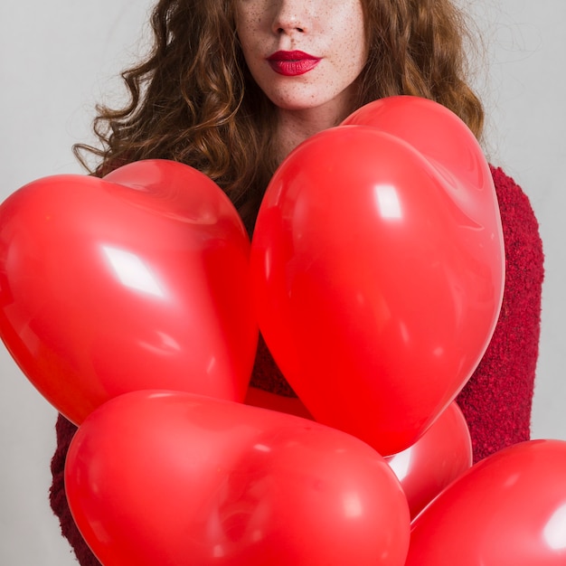 Free photo beautiful woman holding heart balloons