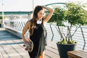 Free photo beautiful woman holding skateboard walking on sidewalk