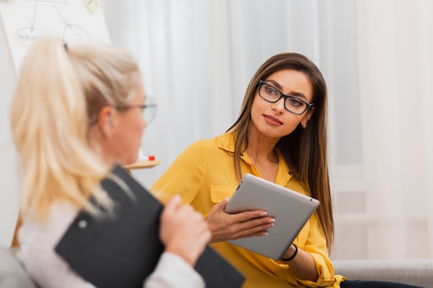 Beautiful woman holding a tablet and looking at her colleague