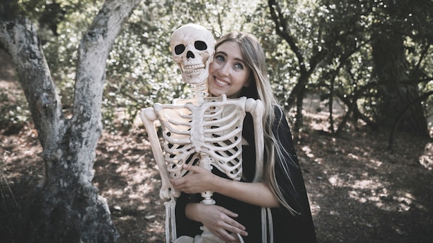 Free Photo beautiful woman hugging behind skeleton