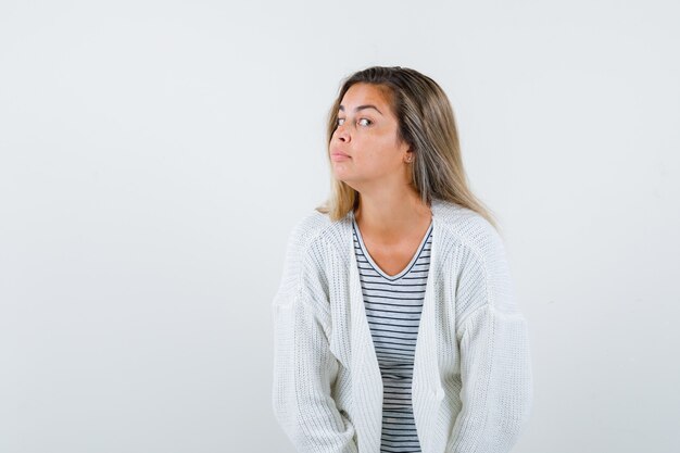 Beautiful woman in jacket, t-shirt standing to hear clearly and looking curious , front view.