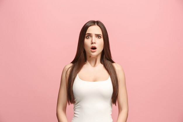 Beautiful woman looking suprised isolated on pink wall