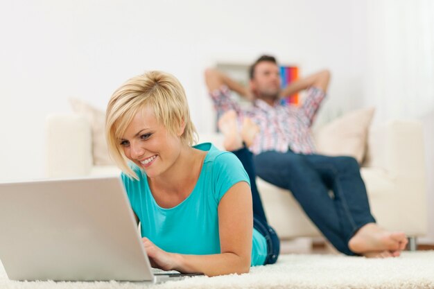 Beautiful woman lying on carpet and using laptop