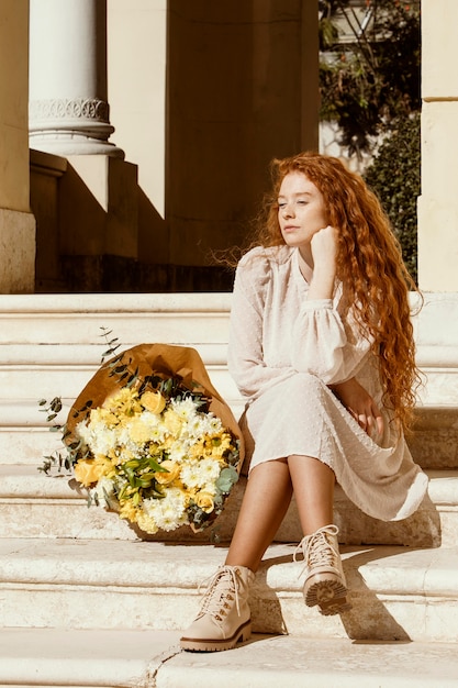 Free photo beautiful woman outdoors with bouquet of spring flowers