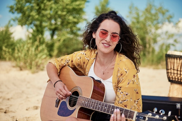 Beautiful woman playing the guitar on the beach