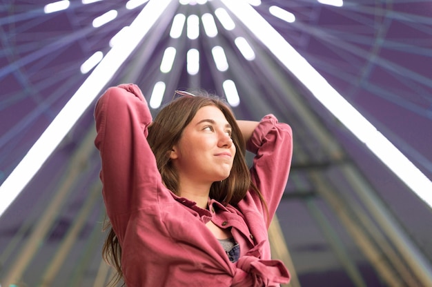 Free photo beautiful woman posing at the amusement park next to big wheel