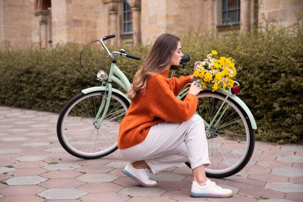 Beautiful woman posing next to bicycle with flowers outdoors