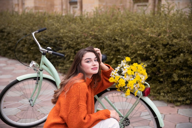 Beautiful woman posing next to bicycle with flowers outside