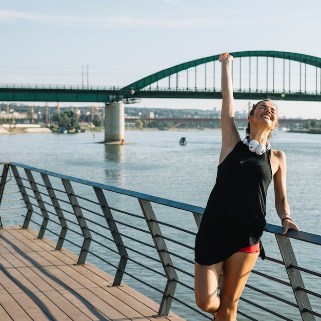 Beautiful woman raising her arms standing near river