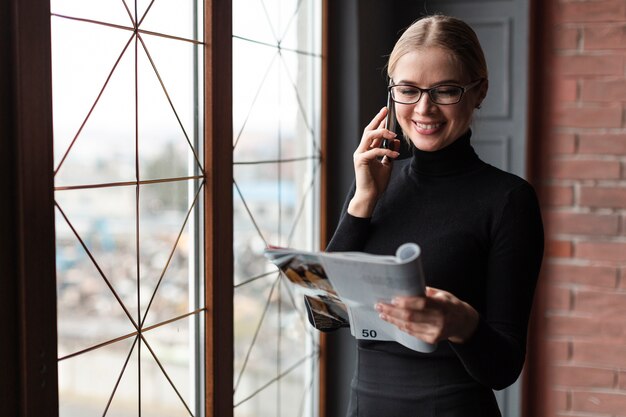 Beautiful woman reading magazine and talking over phone