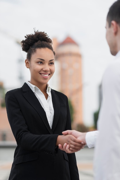 Beautiful woman shaking hands with colleague