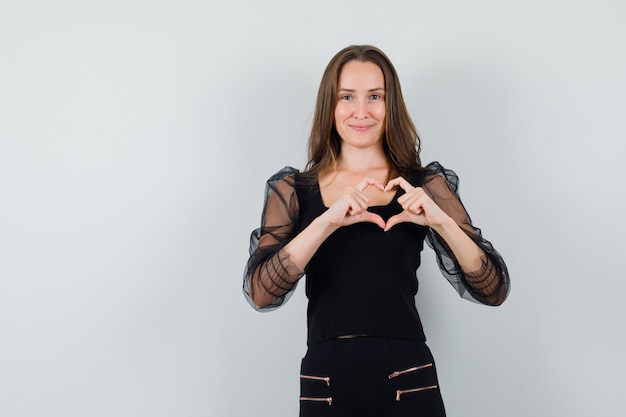 Free photo beautiful woman showing peace gesture in black blouse and looking beloved