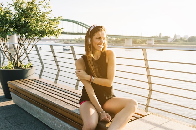 Free Photo beautiful woman sitting nearby river listening to music