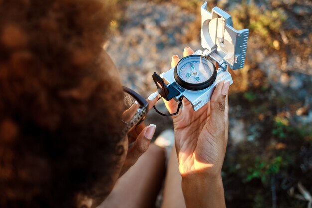 Beautiful woman sitting on rock in canyon, looking at compass