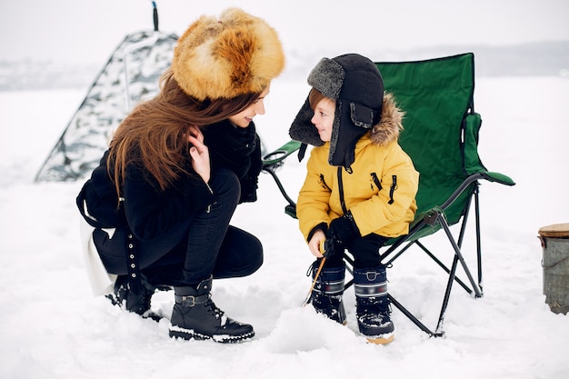 Free Photo beautiful woman sitting on a winter fishing with son