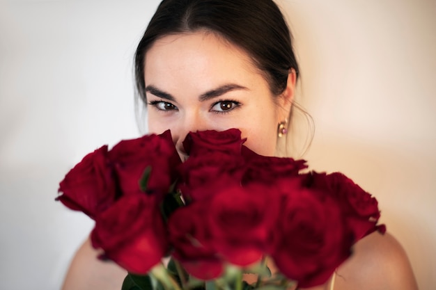 Free photo beautiful woman smiling and holding valentines day bouquet of red roses