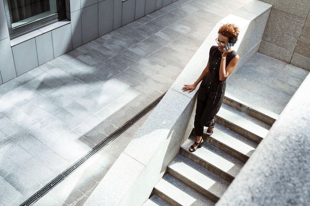 Beautiful woman smiling talking on phone going down stairs