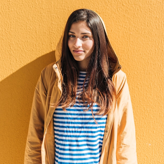 Beautiful woman standing against yellow wall