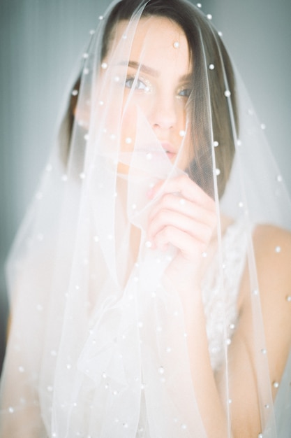 Free photo beautiful woman standing and looking in wedding dress in room