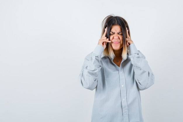 Beautiful woman suffering from strong headache in shirt and looking distressed , front view.