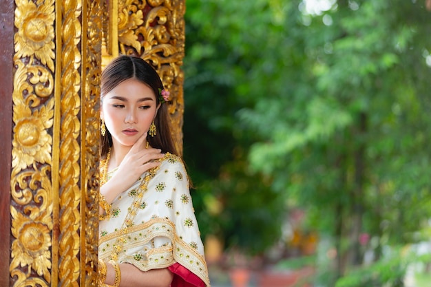 Beautiful woman in thai traditional outfit smiling and standing at temple