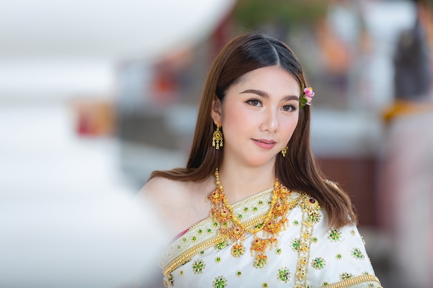 Beautiful woman in thai traditional outfit smiling and standing at temple