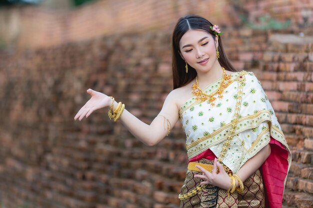 Beautiful woman in thai traditional outfit smiling and standing at temple