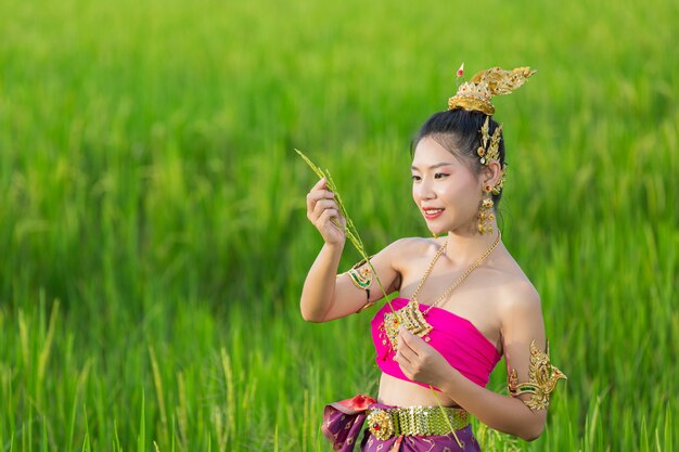 Beautiful woman in thai traditional outfit smiling and standing at temple