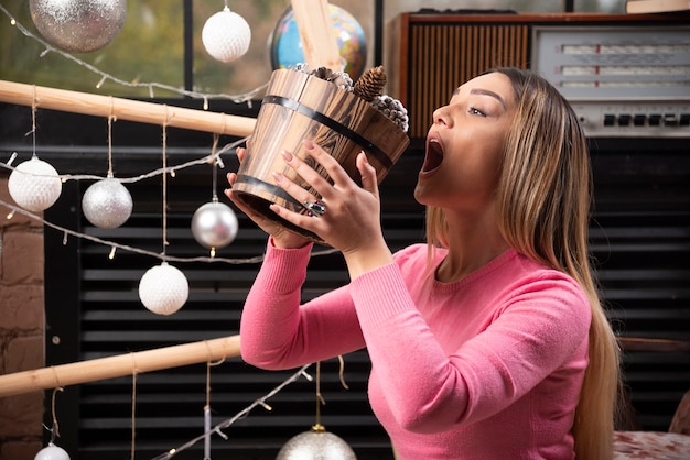 Beautiful woman trying to eat bucket of pinecones at home.