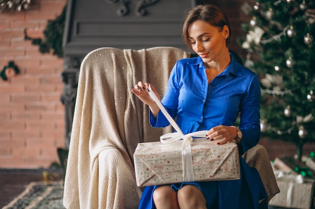 Beautiful woman unpacking presents by Christmas tree