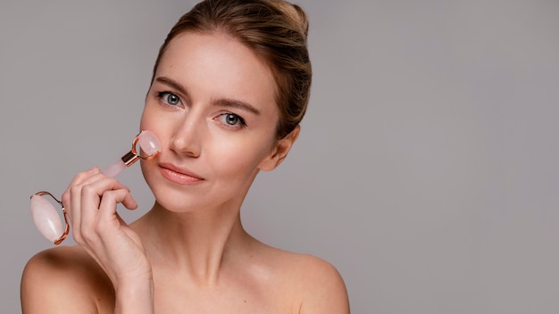 Free photo beautiful woman using a jade roller