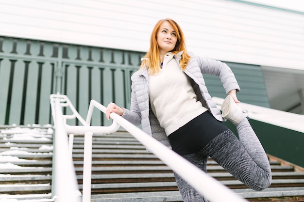 Beautiful woman warming up legs on stairs