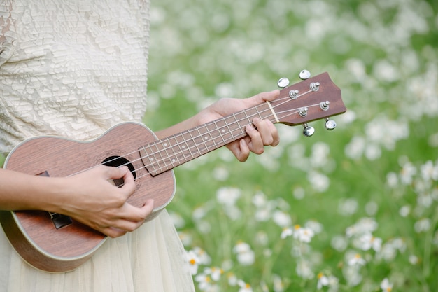 Beautiful woman wearing a cute white dress and holding a ukulele