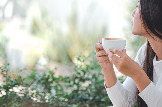 A beautiful woman wearing a long-sleeved white shirt sitting at a coffee shop