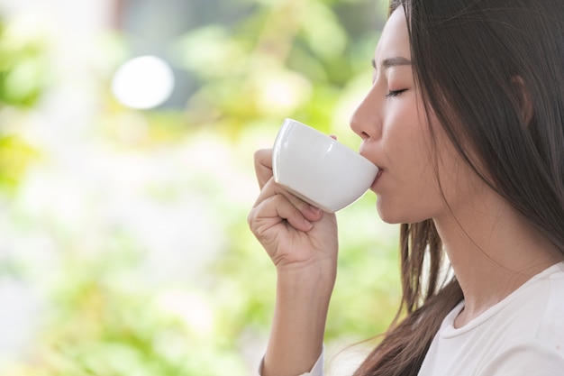 Beautiful woman wearing a long-sleeved white shirt sitting at a coffee shop