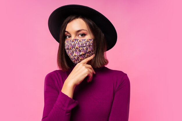 Beautiful woman wearing stylish protective face mask. Black hat