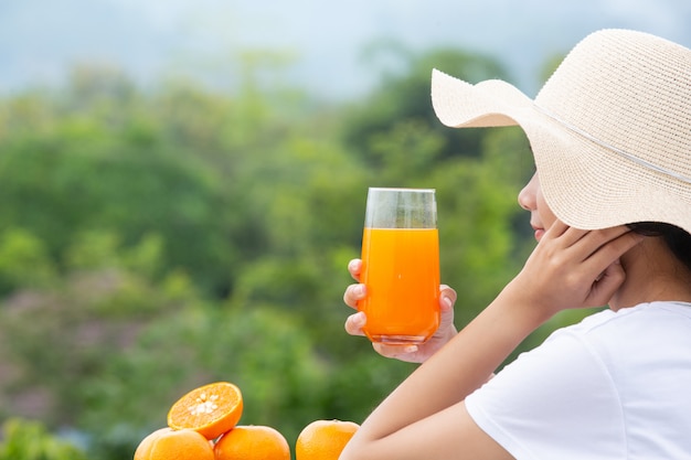 Beautiful woman wearing a white T-shirt holding a glass of orange juice