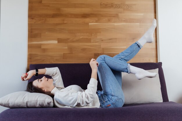 Beautiful woman in white sweater and blue jeans have fun on bad on day time