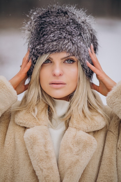 Beautiful woman in winter coat walking in park full of sn ow