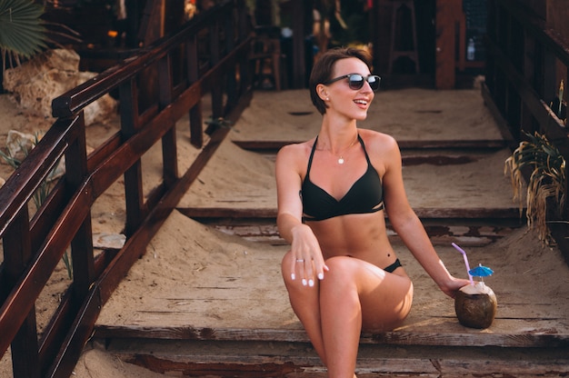 Free Photo beautiful woman with coconut sitting on stairs in bar